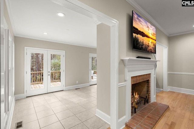 unfurnished living room with visible vents, ornamental molding, french doors, baseboards, and a brick fireplace