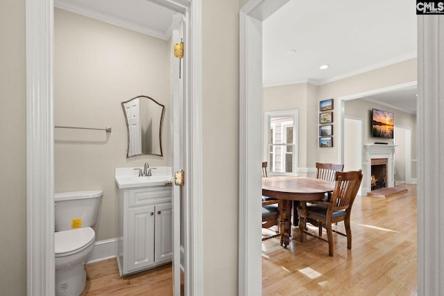 bathroom with ornamental molding, toilet, baseboards, and wood finished floors