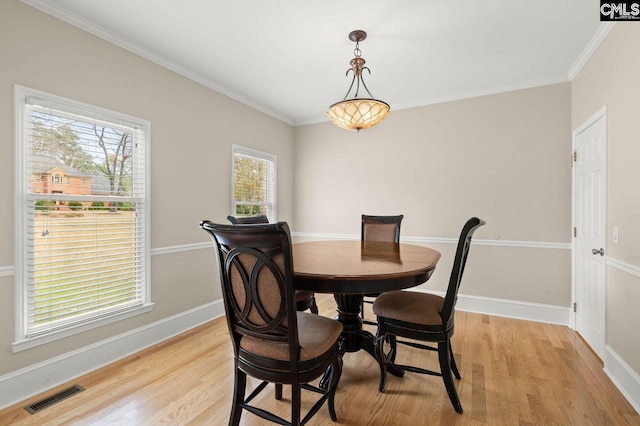 dining space featuring visible vents, baseboards, light wood-style floors, and ornamental molding