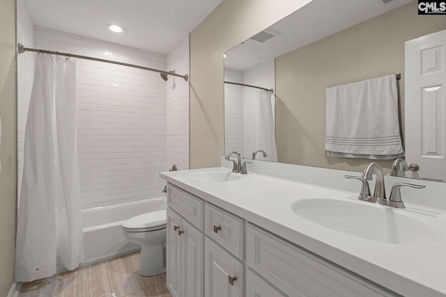 bathroom featuring double vanity, toilet, shower / tub combo with curtain, and a sink