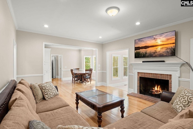 living room with crown molding, baseboards, light wood-type flooring, recessed lighting, and a fireplace