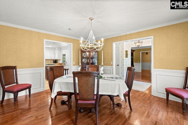 dining room featuring wainscoting, light wood-style floors, and an inviting chandelier