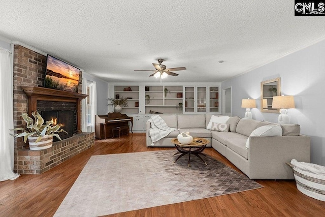 living room featuring a ceiling fan, a textured ceiling, wood finished floors, and a fireplace