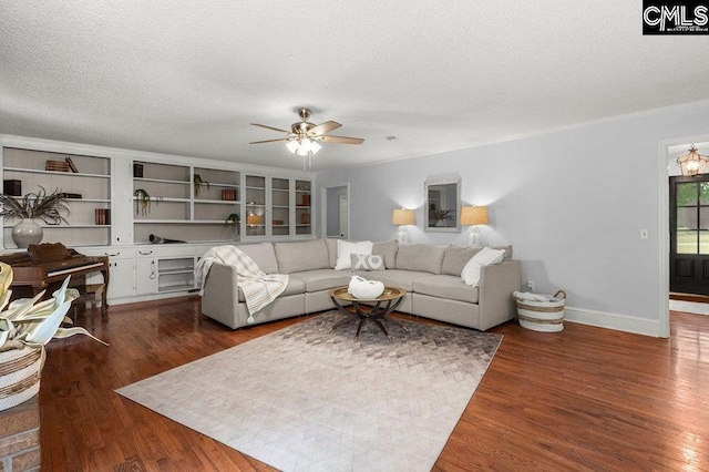 living room featuring ceiling fan, dark wood finished floors, baseboards, and a textured ceiling