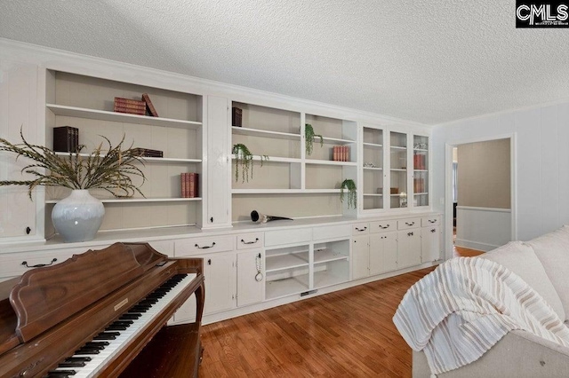 living area featuring built in shelves, a textured ceiling, and wood finished floors