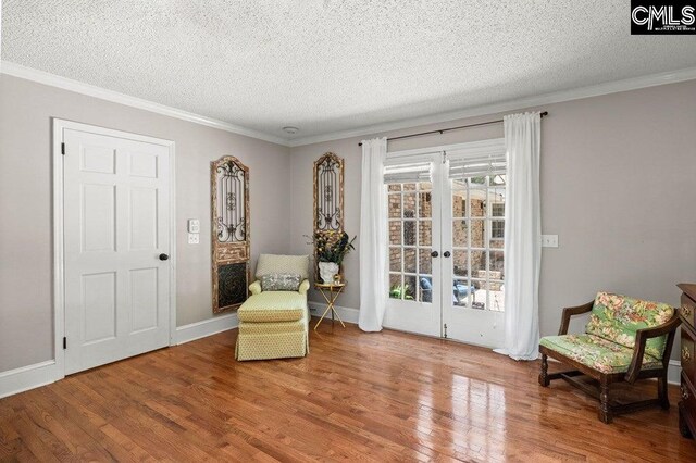 living area featuring french doors, a textured ceiling, light wood-type flooring, and crown molding