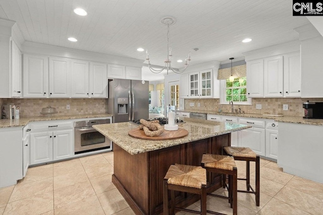 kitchen with backsplash, appliances with stainless steel finishes, wooden ceiling, a kitchen breakfast bar, and white cabinetry