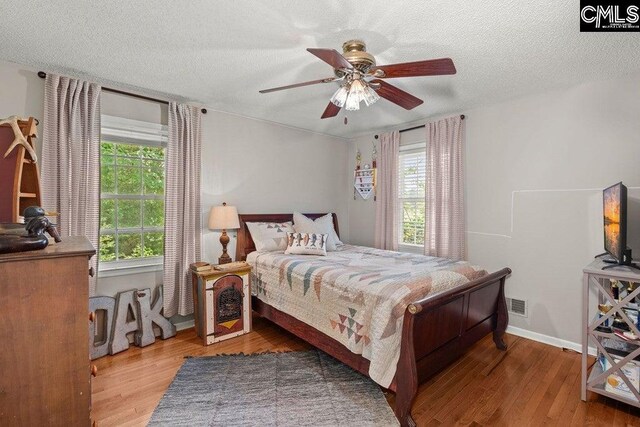 bedroom featuring visible vents, a textured ceiling, and wood finished floors