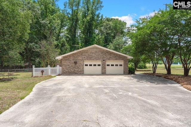 view of side of home with an outbuilding, fence, a detached garage, a lawn, and brick siding