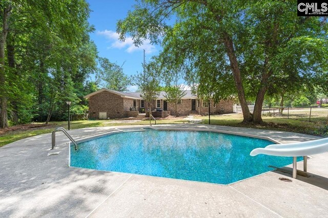 outdoor pool with a patio area and a water slide