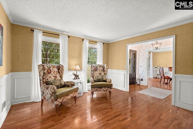 living area with a wainscoted wall and a textured ceiling