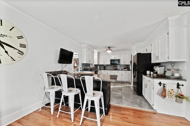 164 Carriageton Dr, Orangeburg, SC 29115 - kitchen with a breakfast bar area, black appliances, white cabinets, and a peninsula