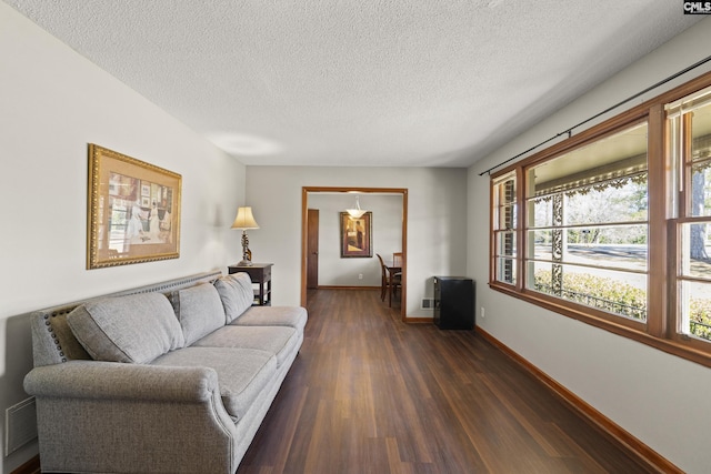 living room with visible vents, a textured ceiling, dark wood-type flooring, and baseboards