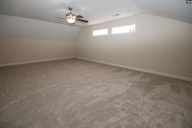 additional living space featuring visible vents, light carpet, baseboards, ceiling fan, and vaulted ceiling