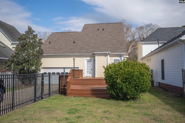 rear view of property featuring fence, an attached garage, a yard, a shingled roof, and a deck