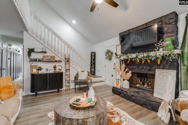 living room featuring a fireplace, stairs, ceiling fan, and wood finished floors