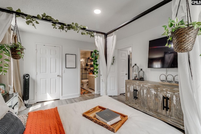 bedroom featuring ensuite bathroom, a textured ceiling, wood finished floors, recessed lighting, and baseboards