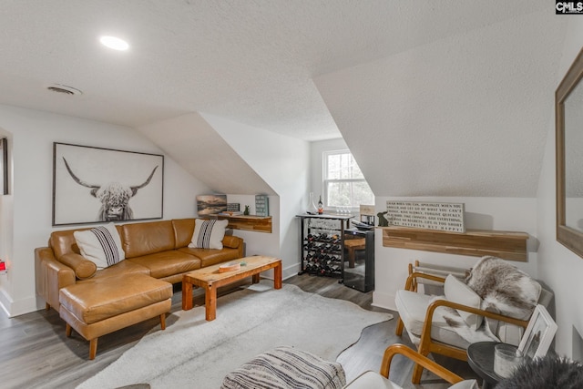 living area with baseboards, a textured ceiling, lofted ceiling, and wood finished floors
