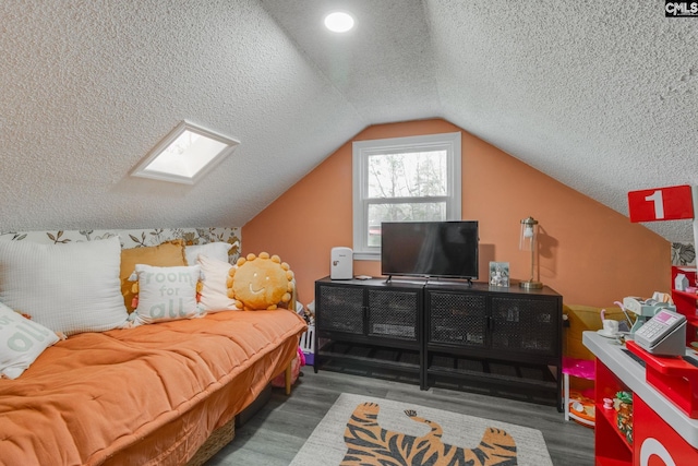 bedroom with vaulted ceiling with skylight, wood finished floors, and a textured ceiling