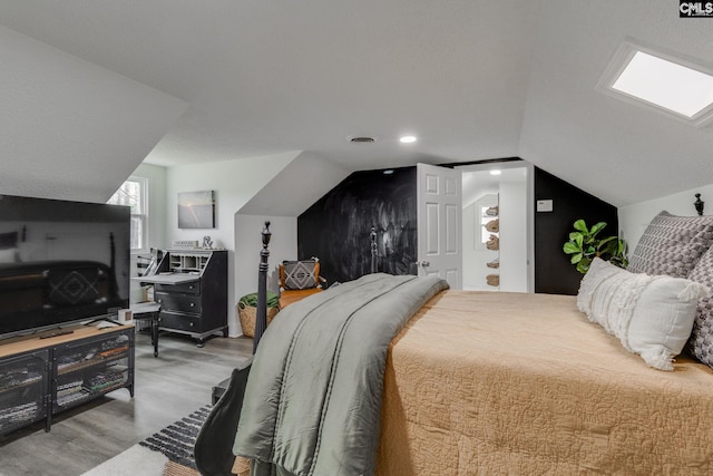 bedroom with visible vents, lofted ceiling, and wood finished floors