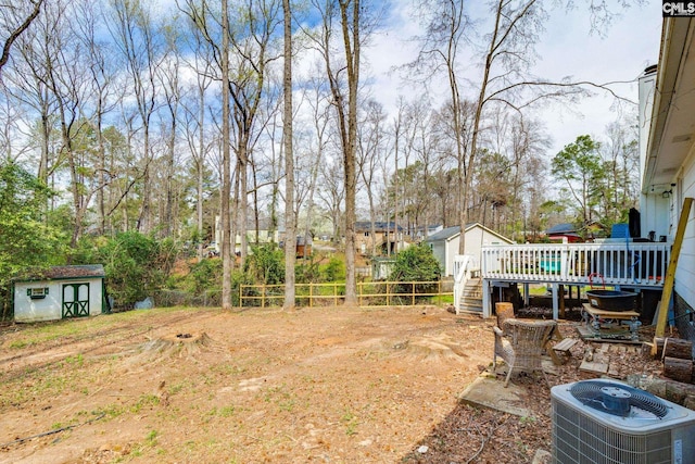 view of yard featuring an outbuilding, central AC, a fenced backyard, a shed, and a wooden deck