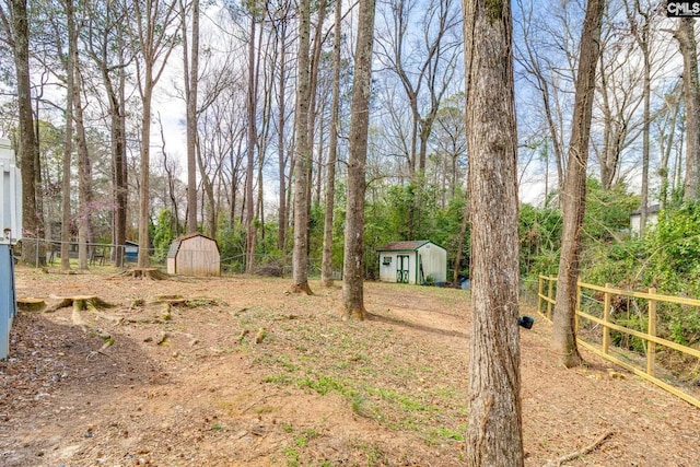 view of yard featuring a storage shed, an outdoor structure, and fence