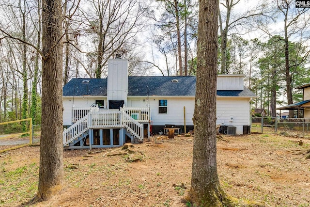 back of property featuring fence, a wooden deck, a chimney, stairs, and a shingled roof