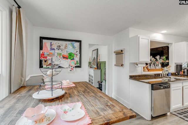 kitchen featuring light wood finished floors, white cabinets, dishwasher, and a textured ceiling