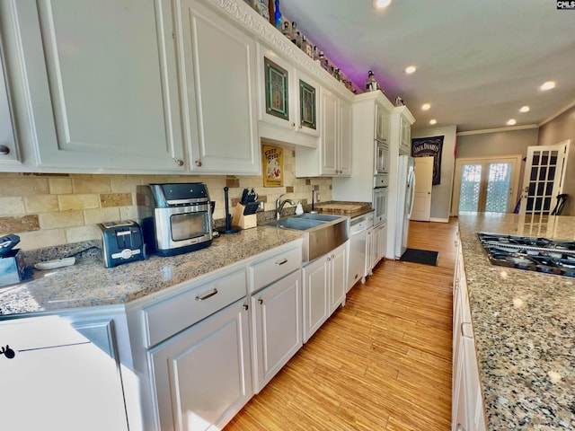 541 Georgia St, Columbia, SC 29201 - kitchen with white appliances, a sink, white cabinets, light wood-style floors, and backsplash