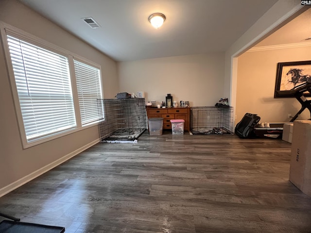 interior space with ornamental molding, wood finished floors, visible vents, and baseboards