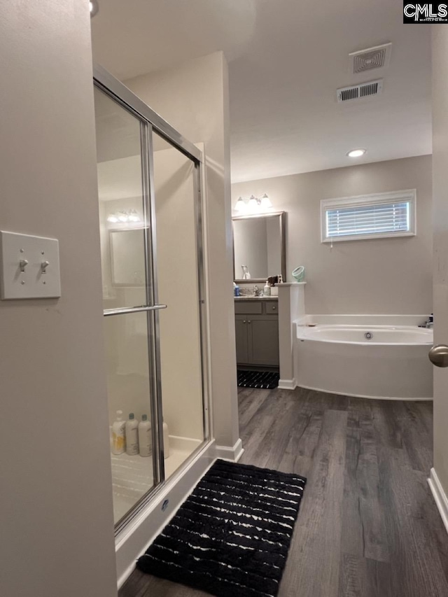 bathroom with vanity, wood finished floors, visible vents, a stall shower, and a garden tub