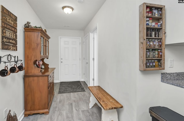 doorway with visible vents, baseboards, and wood finished floors