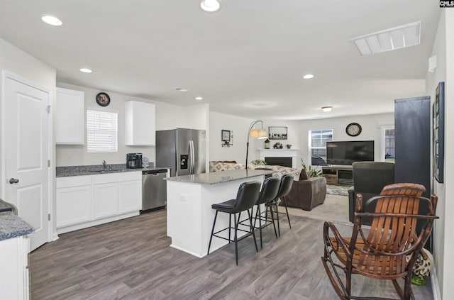 kitchen with a breakfast bar, white cabinetry, visible vents, and appliances with stainless steel finishes