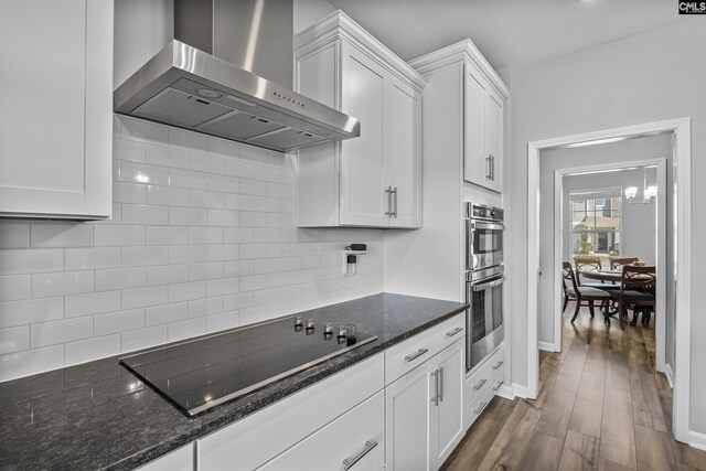 kitchen featuring tasteful backsplash, dark wood finished floors, wall chimney exhaust hood, white cabinets, and black electric stovetop