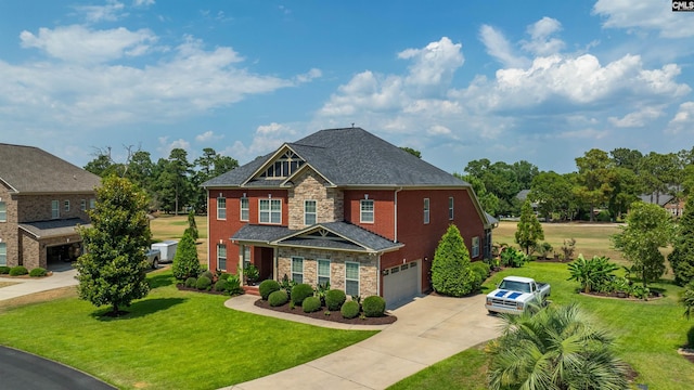 view of front facade featuring a front yard, an attached garage, concrete driveway, stone siding, and brick siding