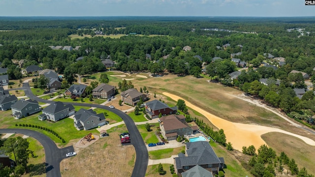 drone / aerial view featuring view of golf course, a wooded view, and a residential view