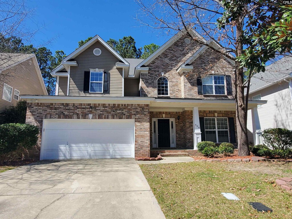 view of front of home with driveway, brick siding, a garage, and a front yard