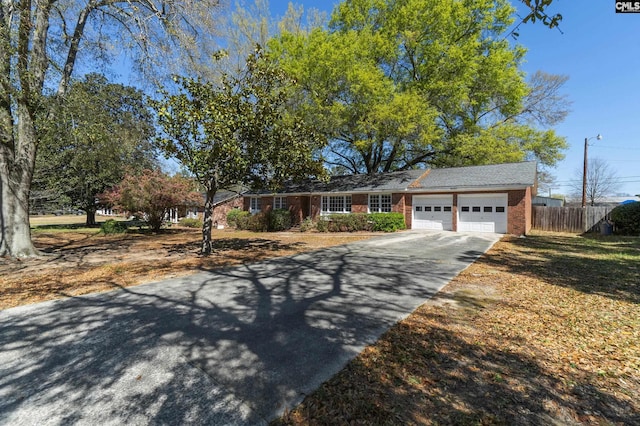 ranch-style house featuring brick siding, concrete driveway, a garage, and fence