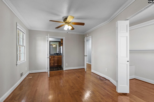 unfurnished bedroom featuring a closet, wood finished floors, baseboards, visible vents, and ornamental molding