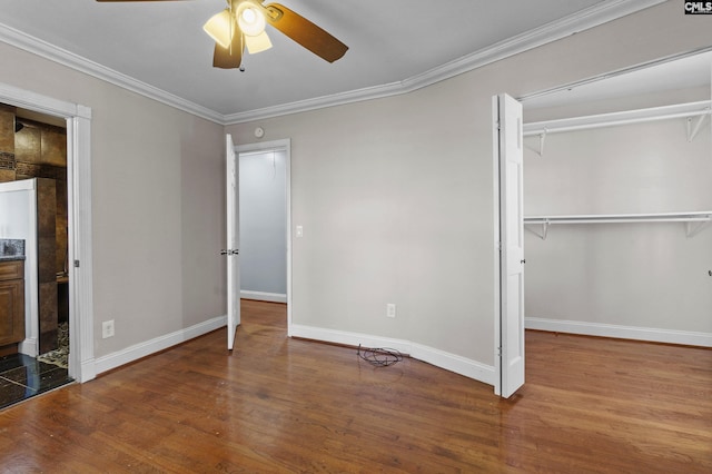 unfurnished bedroom with a closet, baseboards, ornamental molding, wood finished floors, and a ceiling fan