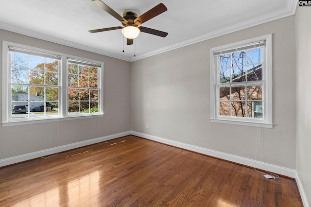 empty room with baseboards, crown molding, wood finished floors, and a ceiling fan
