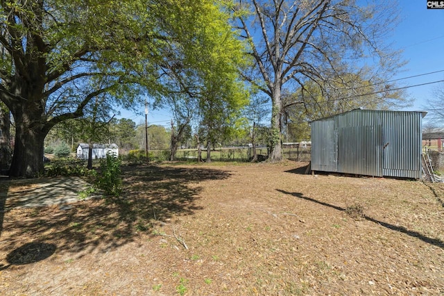 view of yard featuring a storage unit, an outbuilding, and fence