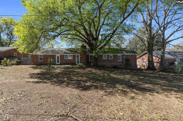single story home with brick siding, a chimney, and fence