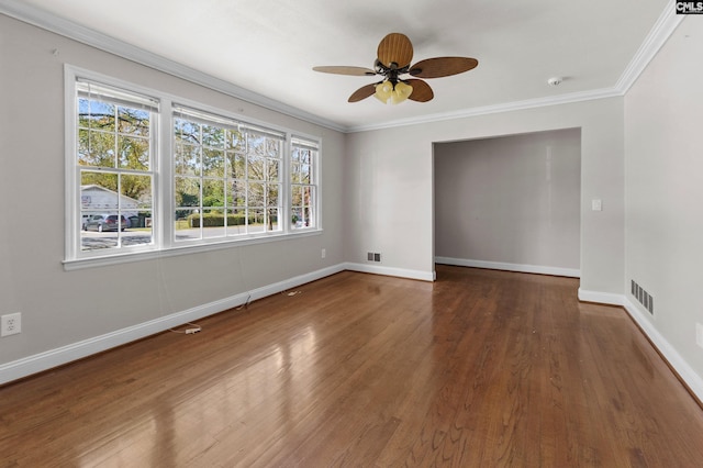 empty room with a ceiling fan, crown molding, baseboards, and wood finished floors