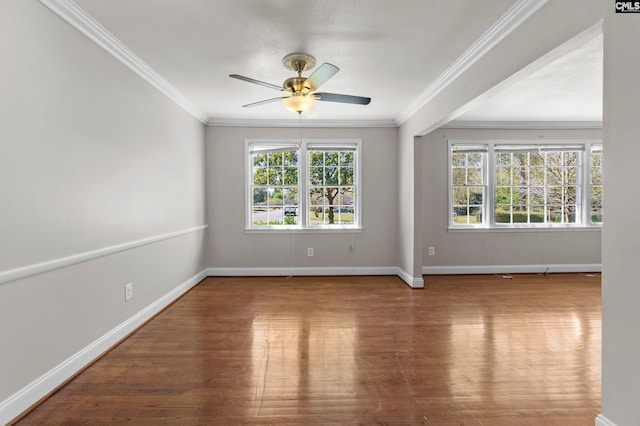 spare room with wood finished floors, ornamental molding, baseboards, and ceiling fan