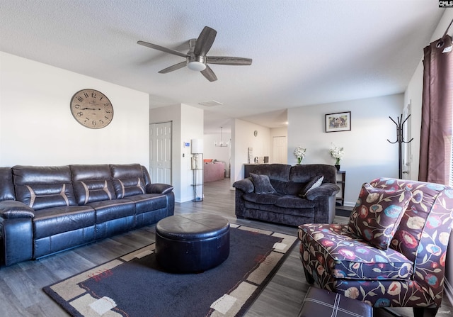 living area featuring wood finished floors, a textured ceiling, baseboards, visible vents, and ceiling fan