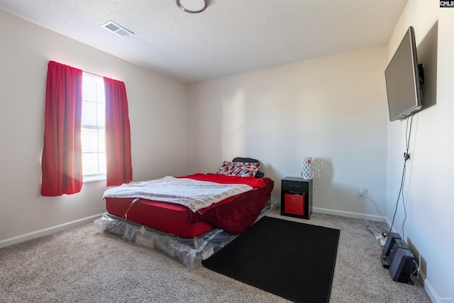 carpeted bedroom with baseboards, visible vents, and a textured ceiling