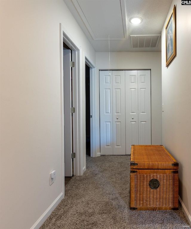 hallway featuring attic access, baseboards, visible vents, and carpet floors