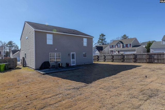 rear view of property featuring a fenced backyard, a residential view, a yard, and a patio area