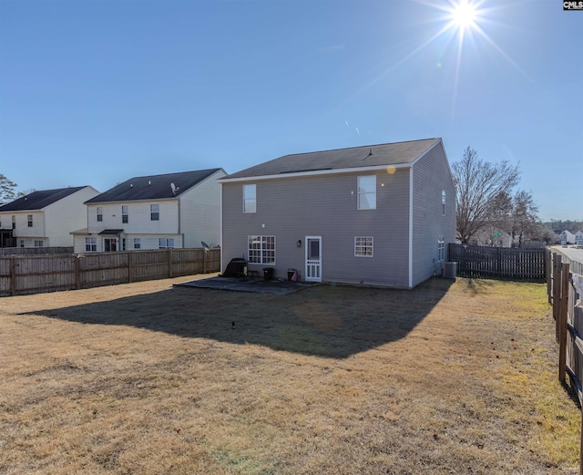 rear view of property featuring central air condition unit, a residential view, a fenced backyard, and a yard